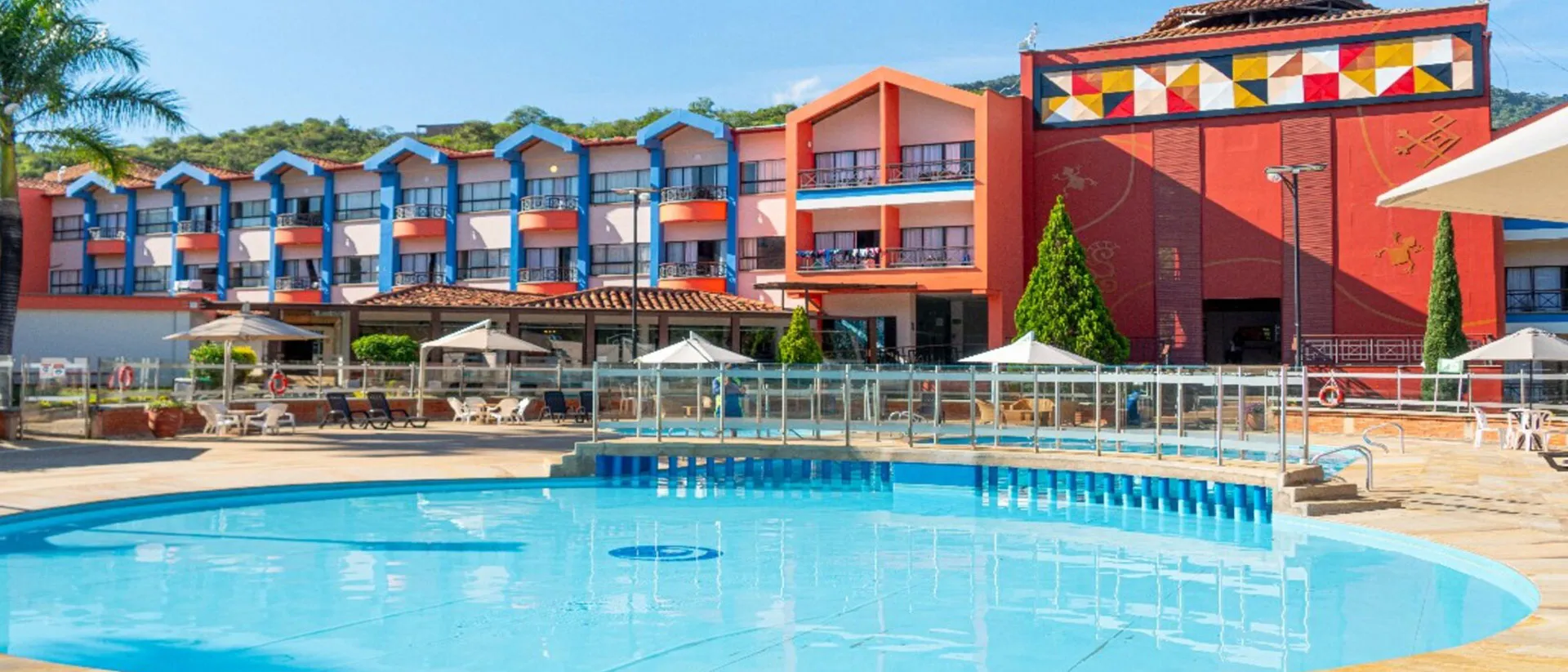 Piscina al aire libre rodeada con un colorido edificio de fondo