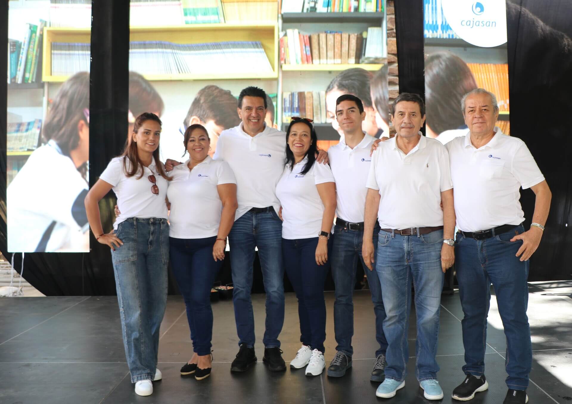Grupo de siete personas en inauguración, con camisetas blancas y jeans