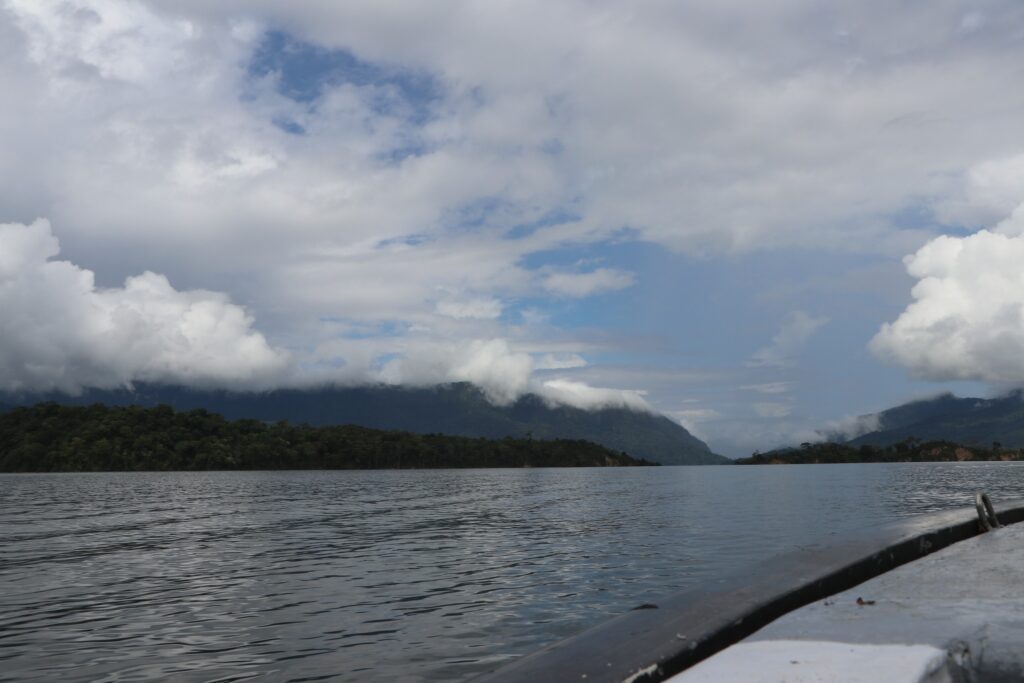 Embalse rodeado de montañas con nubes bajas, visto desde una embarcación.
