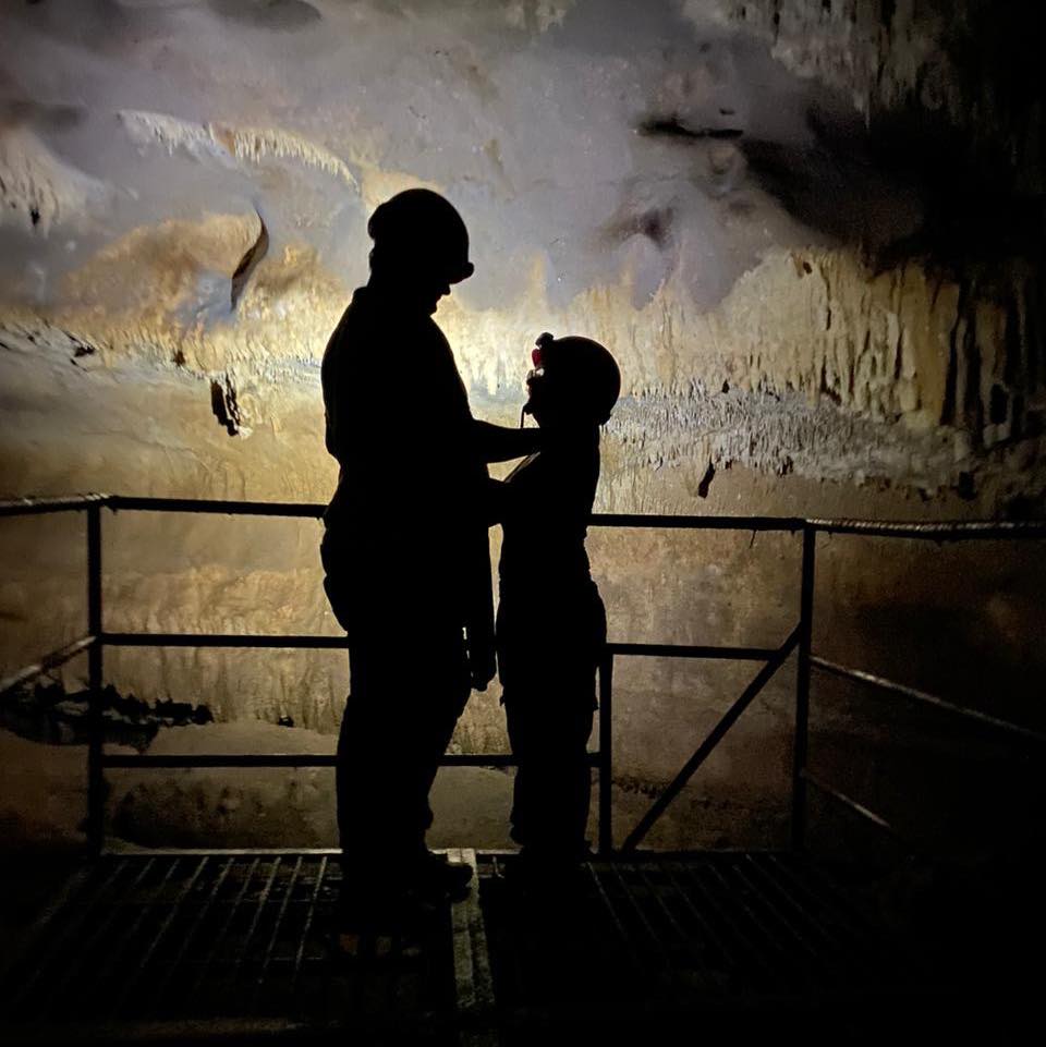 Exploración en cueva con dos personas usando cascos con linterna, iluminados contra la roca.