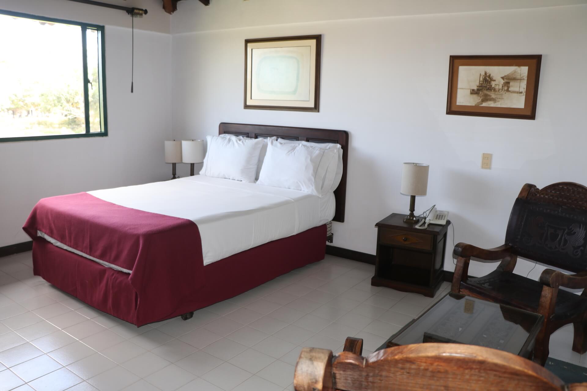 Alojamiento en la Mesa de los Santos Habitación con cama matrimonial, muebles de madera, lámparas y ventana con luz natural.