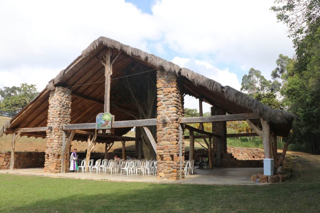 Estructura rústica con techo de palma y columnas de piedra en un entorno natural
