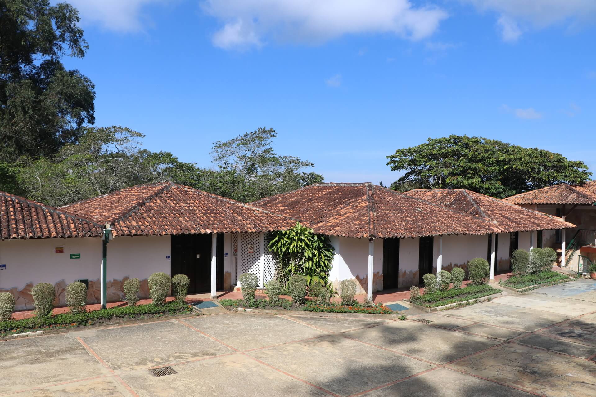 Cabañas de estilo colonial con techos de teja y paredes blancas, rodeadas de jardines y vegetación.