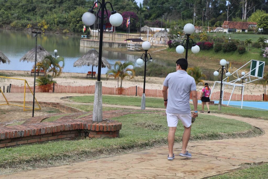 Sendero empedrado con faroles y áreas verdes, junto al lago