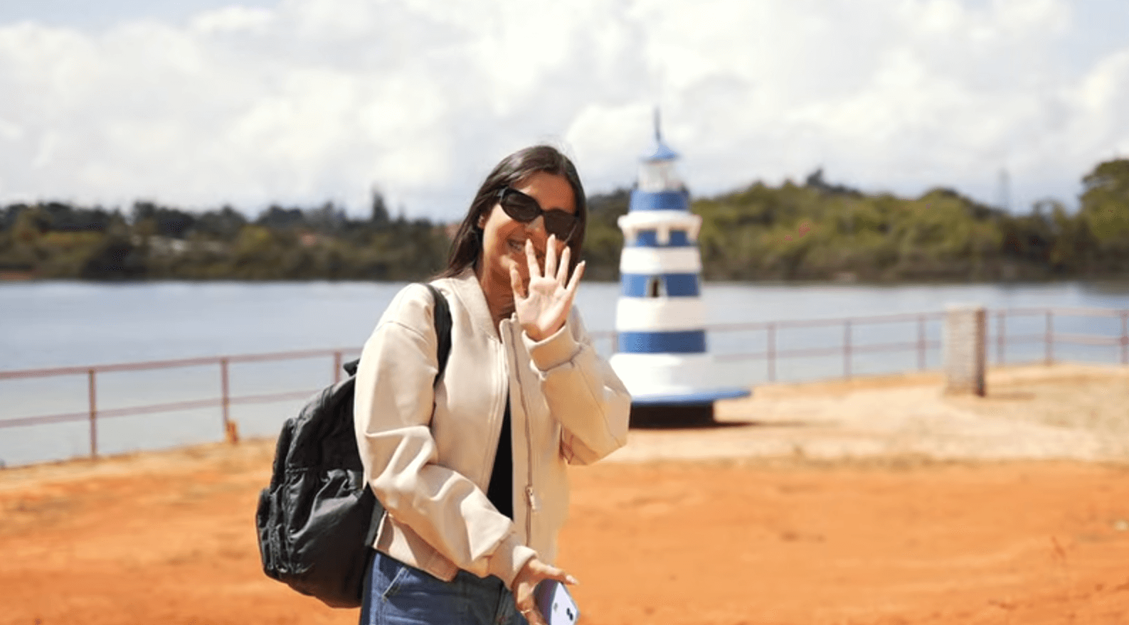 Mujer sonriendo y saludando junto a lago del Parque Acuarela Cajasan