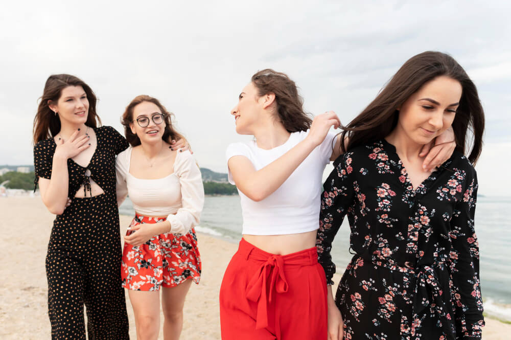 Grupo de cuatro mujeres caminando juntas por la playa, disfrutando de un viaje en compañía