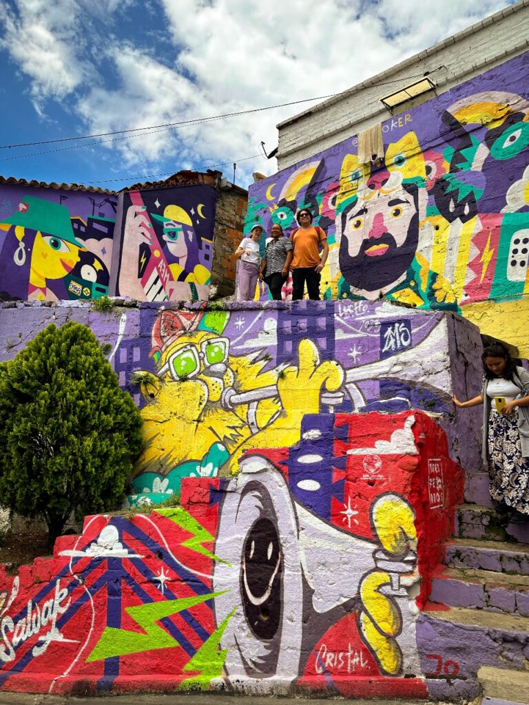 Grupo de personas en escaleras decoradas con murales coloridos en un barrio de Bucaramanga