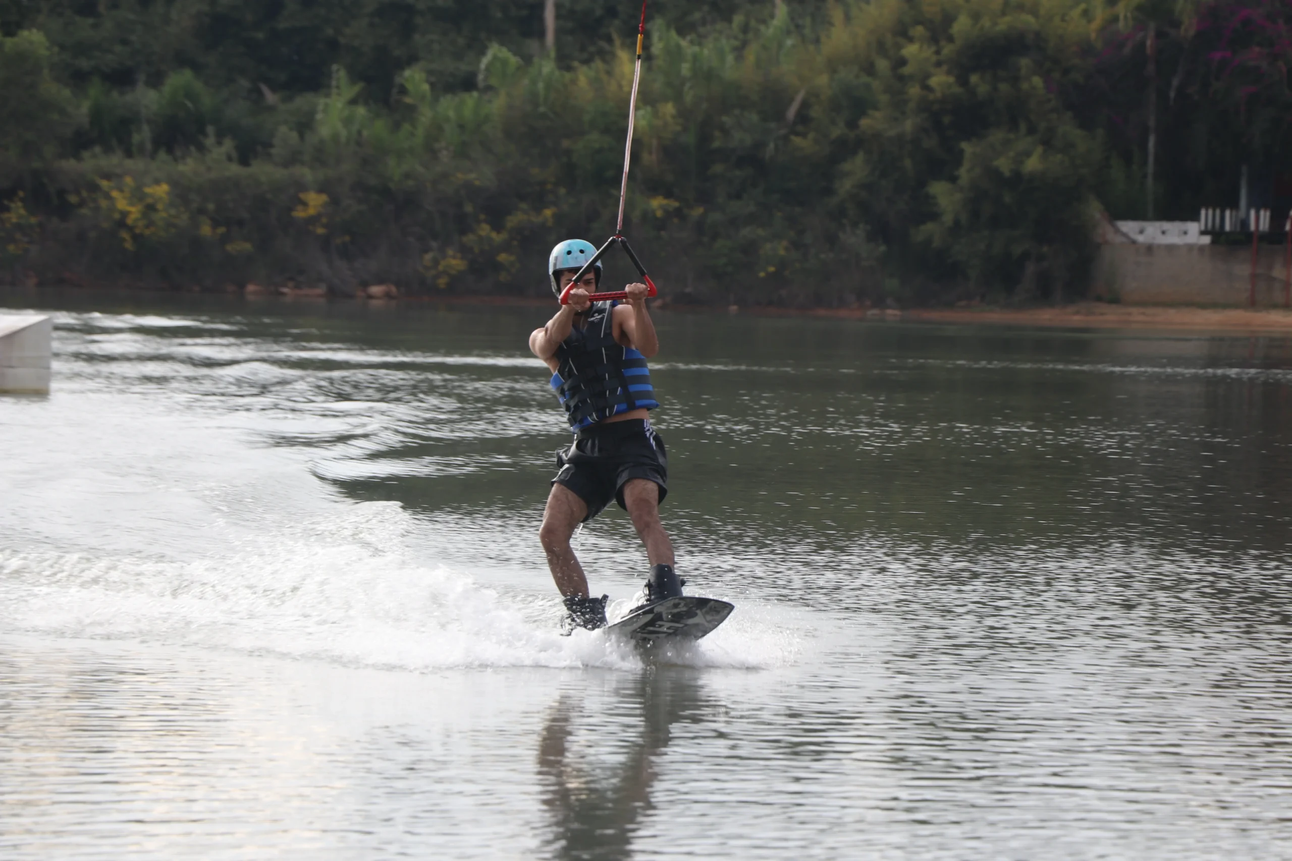 Hombre practicando wakeboard en el lago Acuarela mientras es jalado por un cable